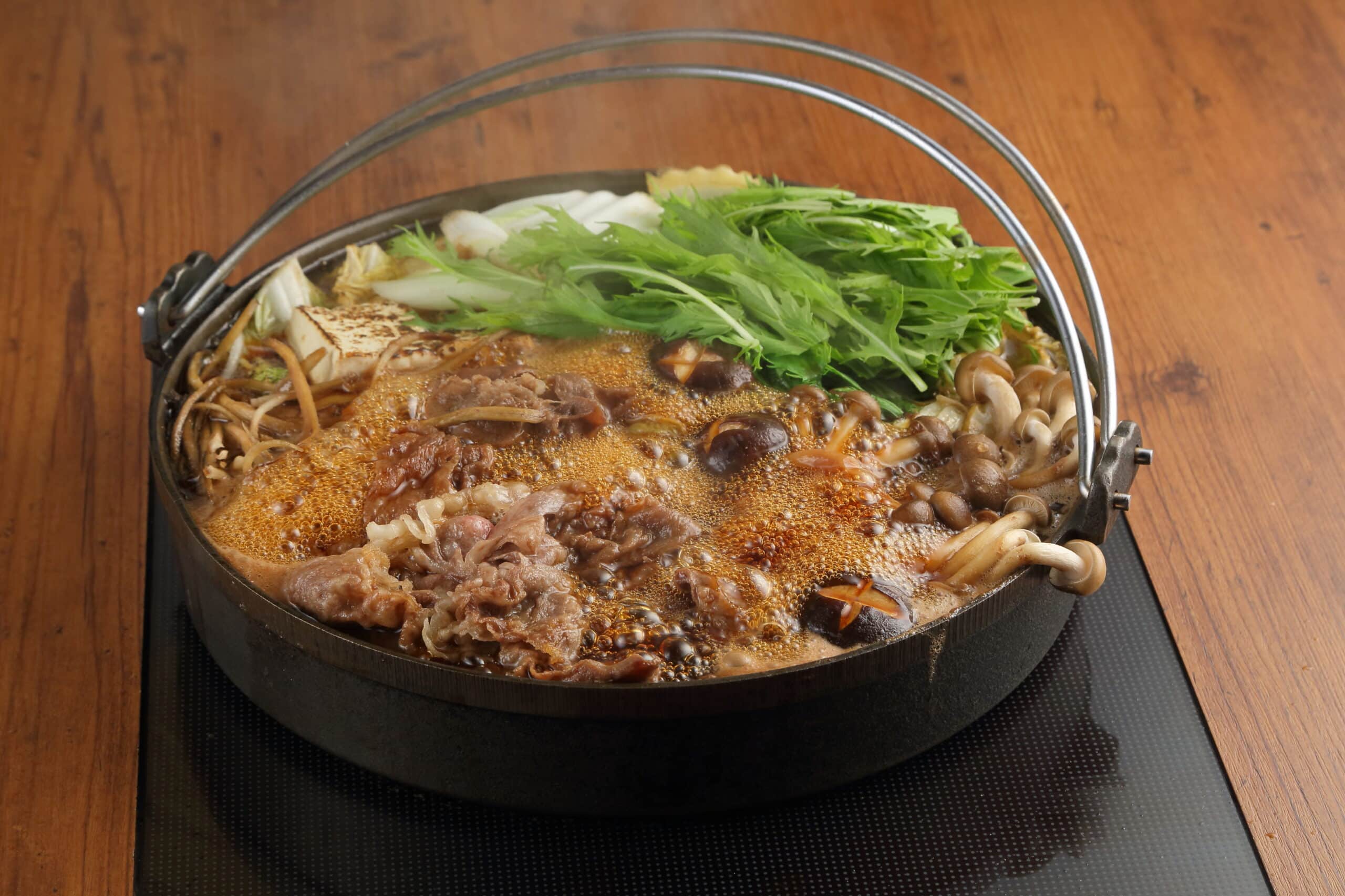黒鍋で仕上げるすき焼きの牛肉と青ねぎ